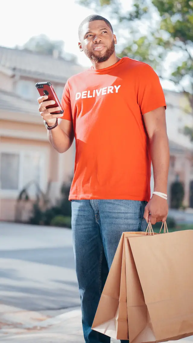 man delivering food is searching for address with phone in hand