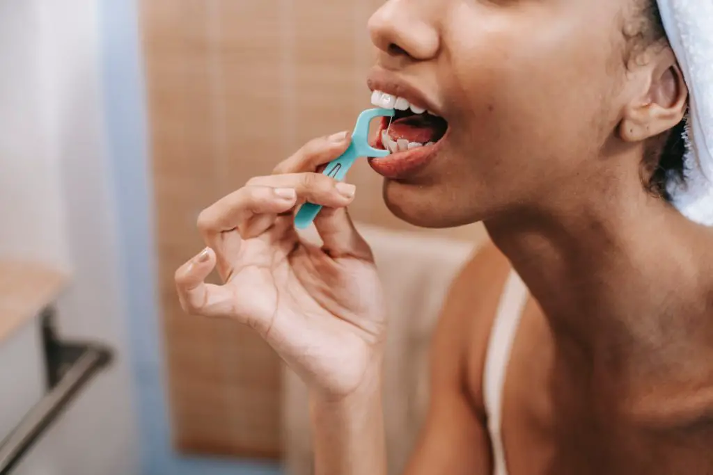 black woman flossing her teeth