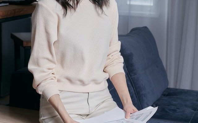 Woman Sitting on a Couch Looking at Tax Forms